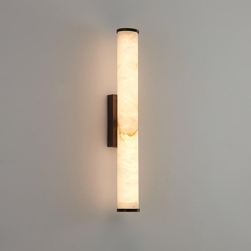 Brass wall sconce with veined alabaster shade casting soft uplight