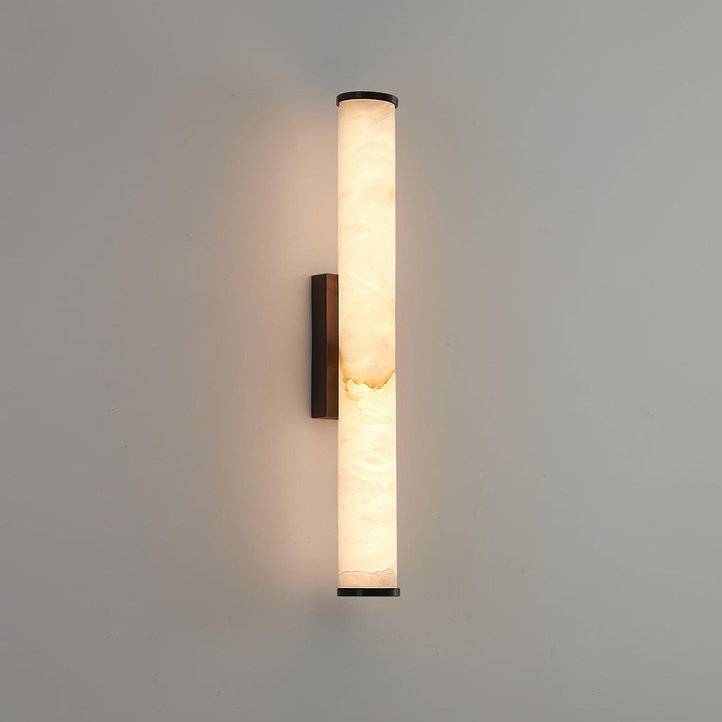 Alabaster wall sconce glowing warmly on a textured interior wall