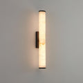 Alabaster wall sconce glowing warmly on a textured interior wall