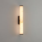 Alabaster wall sconce glowing warmly on a textured interior wall