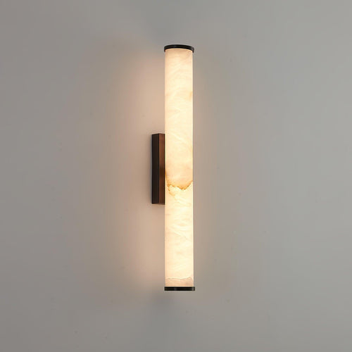 Alabaster wall sconce glowing warmly on a textured interior wall