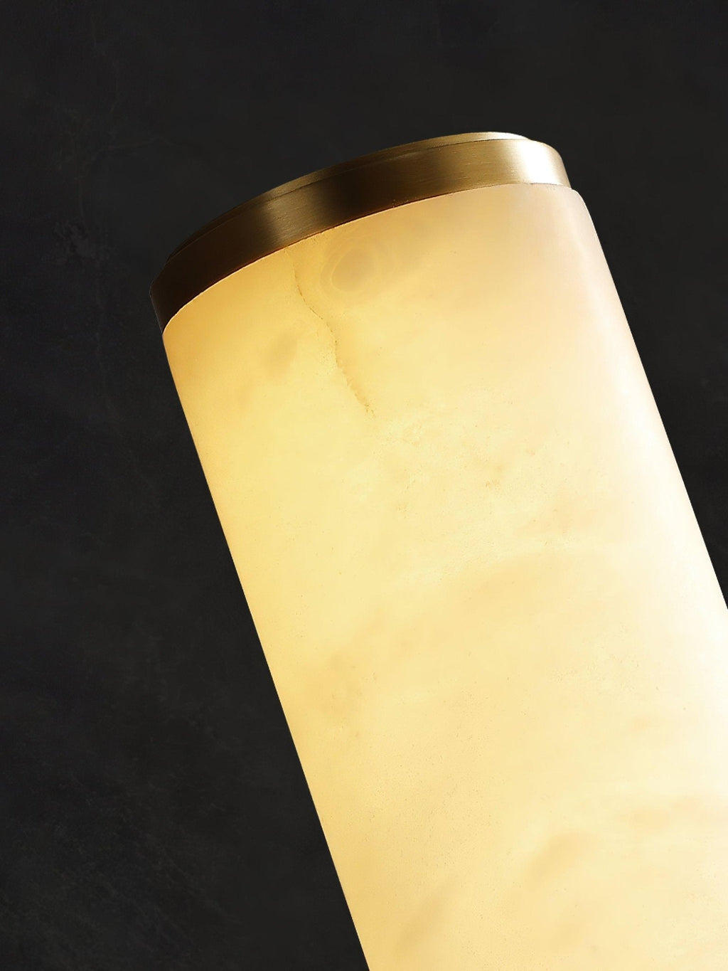 Alabaster wall sconce detail with brass arm and canopy plate