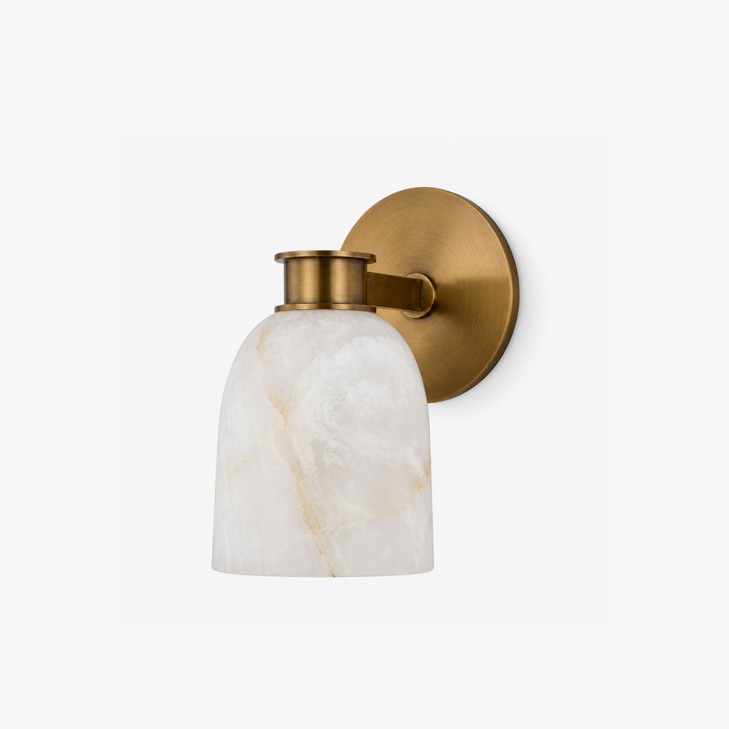 Studio shot of this Clérachic wall sconce in brass finish, its bell-shaped alabaster shade catching soft light.