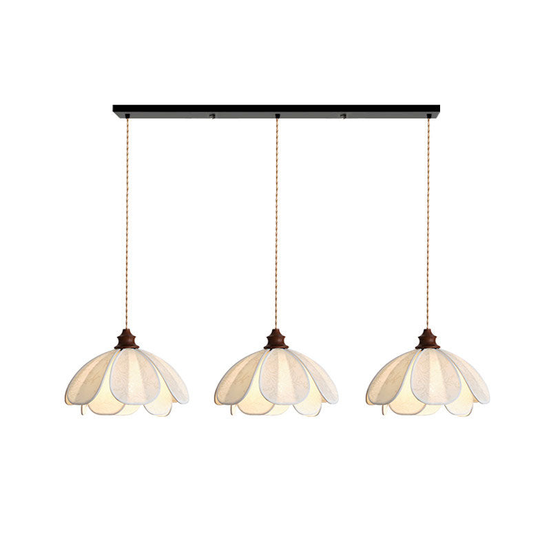 Three shades of this Clérachic pendant hang lit from a black linear bar against a plain backdrop.