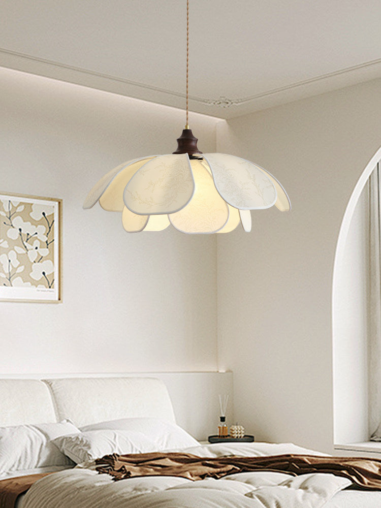 In a white bedroom with an arched doorway, this Clérachic pendant glows above an unmade bed.