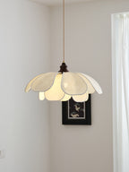 In a corner near a dark-framed picture, this Clérachic pendant's petal shade glows softly.