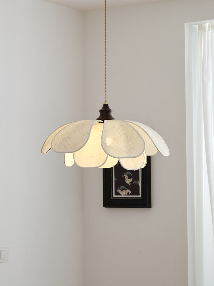 In a corner near a dark-framed picture, this Clérachic pendant's petal shade glows softly.