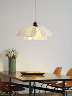 Fresh flowers and a brass tray sit beneath this glowing Clérachic pendant at a long wood dining table.