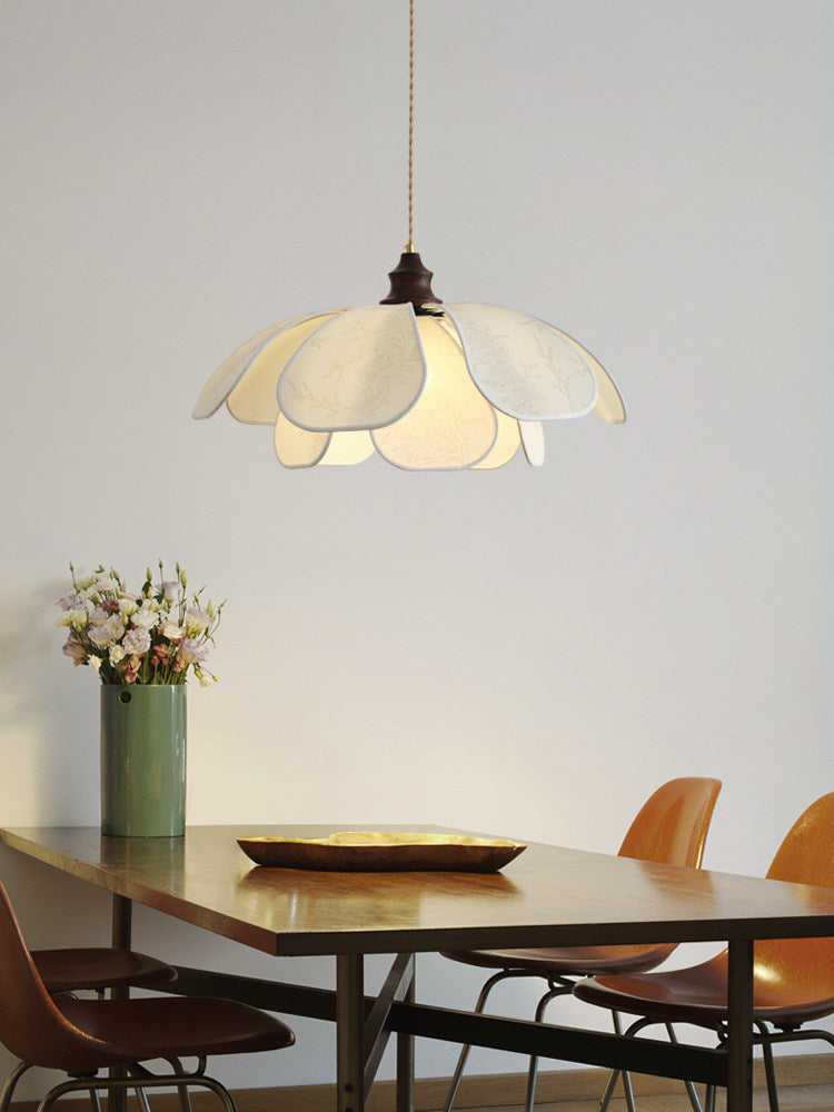 Fresh flowers and a brass tray sit beneath this glowing Clérachic pendant at a long wood dining table.
