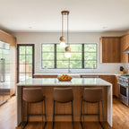 A single Clérachic pendant lights a farmhouse kitchen island holding a bowl of oranges.