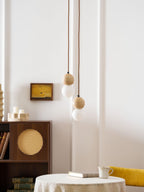 Two Clérachic pendants of differing lengths hang near candle holders and a rattan-fronted cabinet.