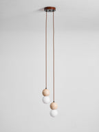 A two-light Clérachic pendant's round canopy drops two cords ending in small travertine and glass spheres, studio shot.