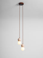 Two short cords drop small travertine and glass spheres from this Clérachic pendant's round canopy, studio shot on grey.