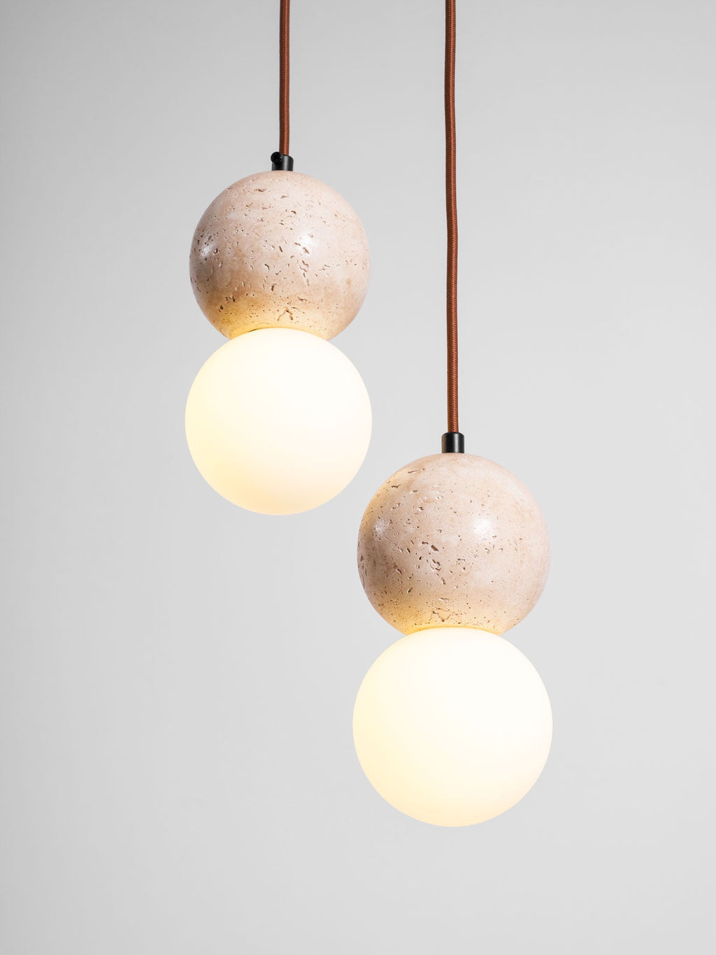 Two lit two-tier Clérachic pendants hang side by side against a plain grey backdrop.