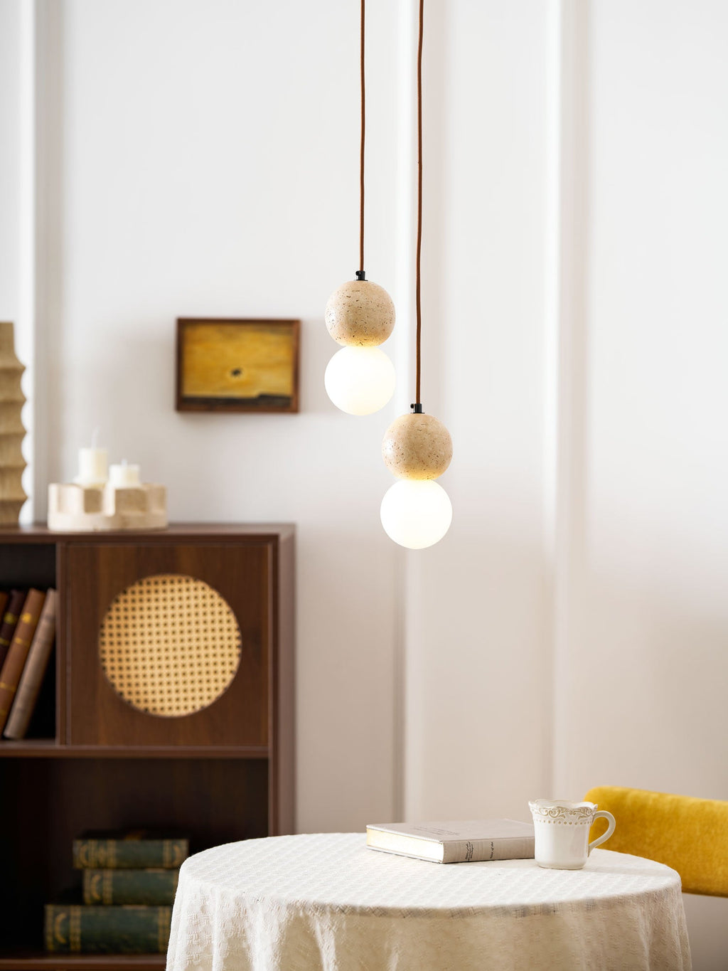 A two-tier Clérachic pendant hangs above a round table holding a cup and a stack of books.