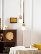 A two-tier Clérachic pendant hangs above a round table holding a cup and a stack of books.