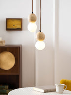 A two-tier Clérachic pendant glows close beside a rattan-fronted cabinet and small framed artwork.