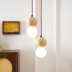 Warm light glows from the opal glass globe beneath this Clérachic pendant's travertine sphere.