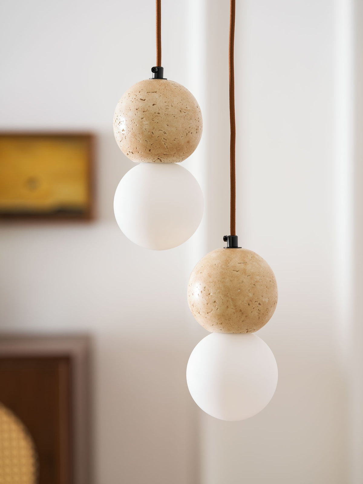 Fine mineral flecks mark the travertine sphere on this Clérachic pendant, paired with an opal glass globe below.
