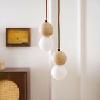 Two two-tier Clérachic pendants hang side by side near a rattan-fronted cabinet.