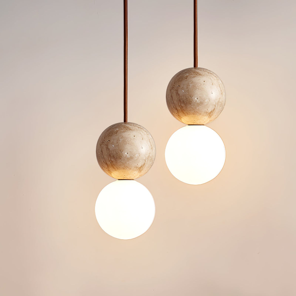 Warm light catches the travertine sphere of this Clérachic pendant, seen close above its opal glass globe.