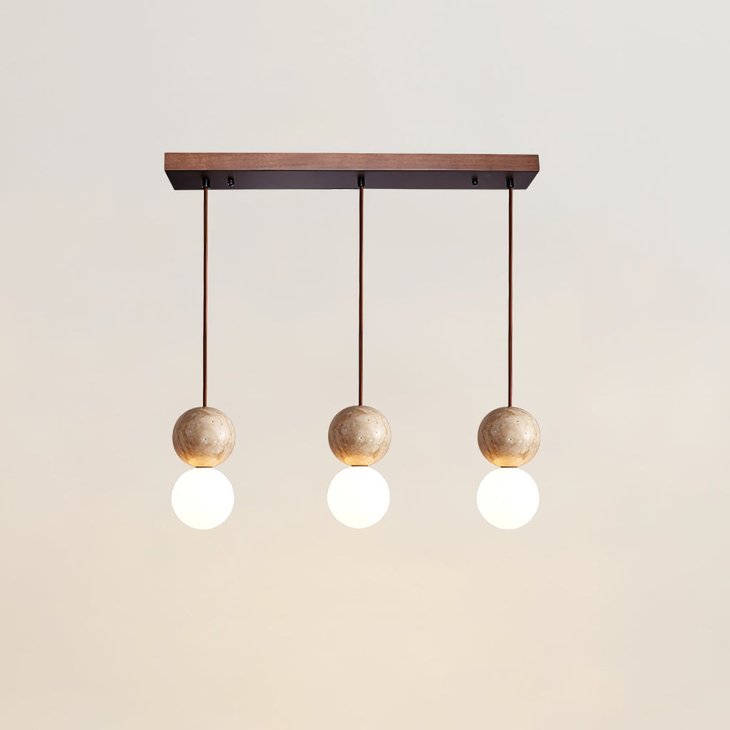 Three travertine and glass spheres line up beneath a long canopy on this Clérachic pendant, studio shot on white.