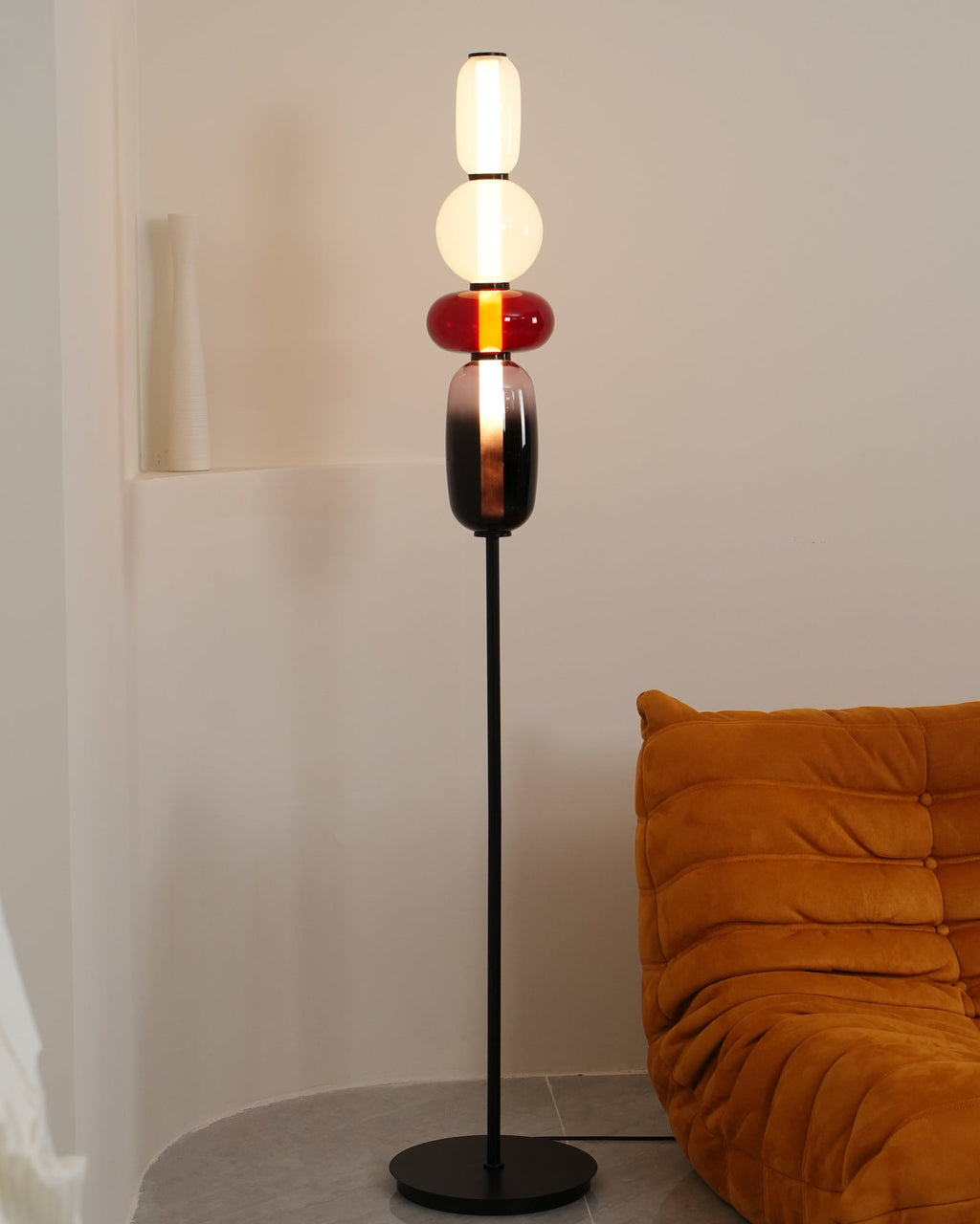 Hand-blown glass floor lamp standing in a bright living space