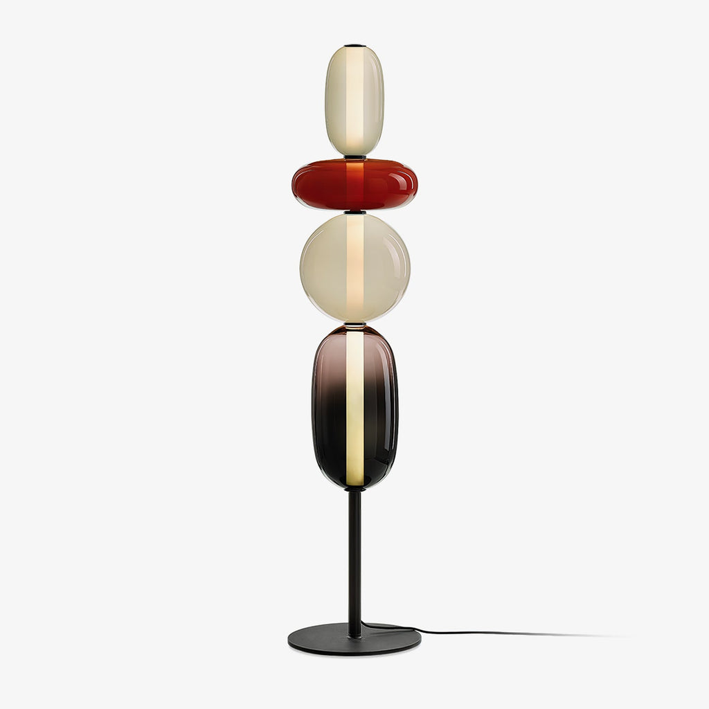 Hand-blown glass floor lamp casting warm light on a wall