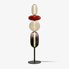 Hand-blown glass floor lamp casting warm light on a wall