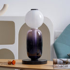 Hand-blown glass table lamp glowing in an evening interior
