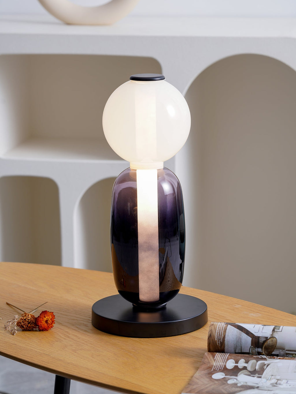 Hand-blown glass table lamp glowing in a styled corner