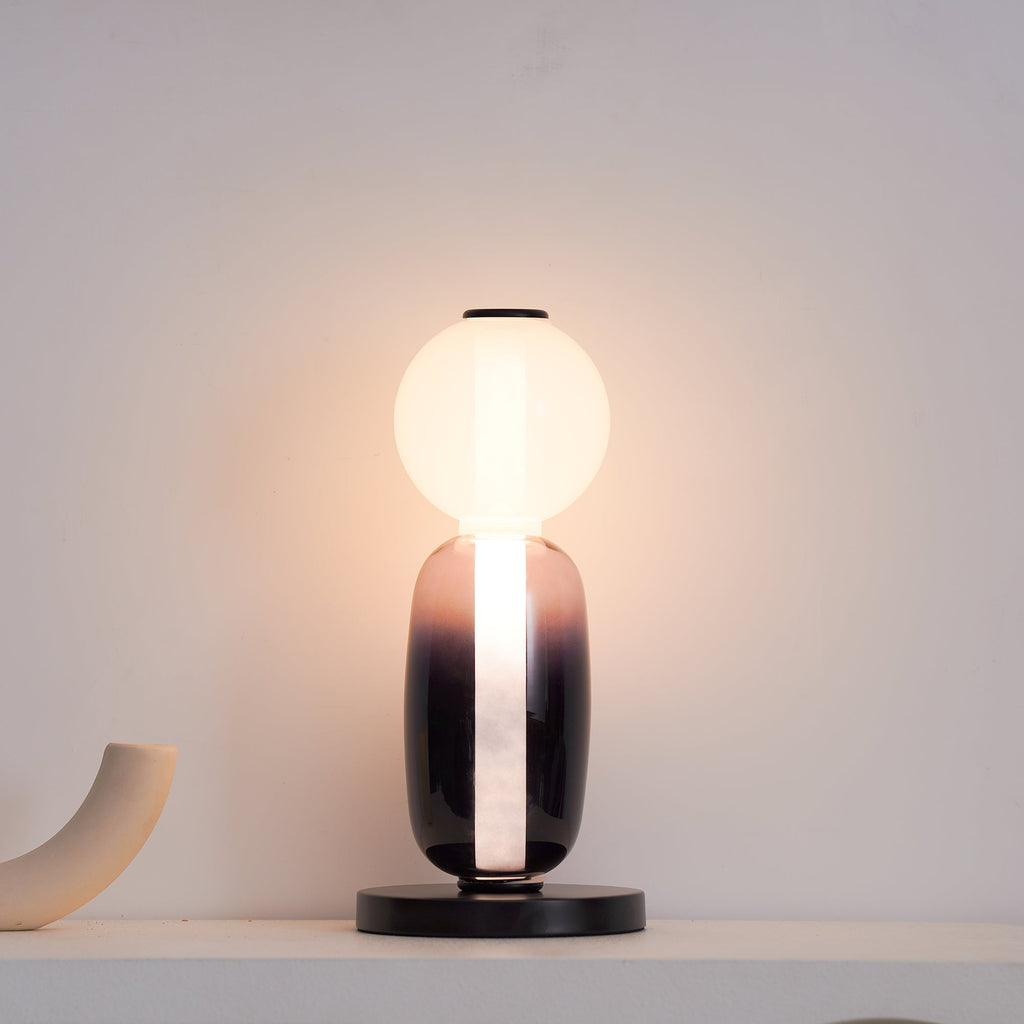 Crystal pebble table lamp lit beside a soft armchair