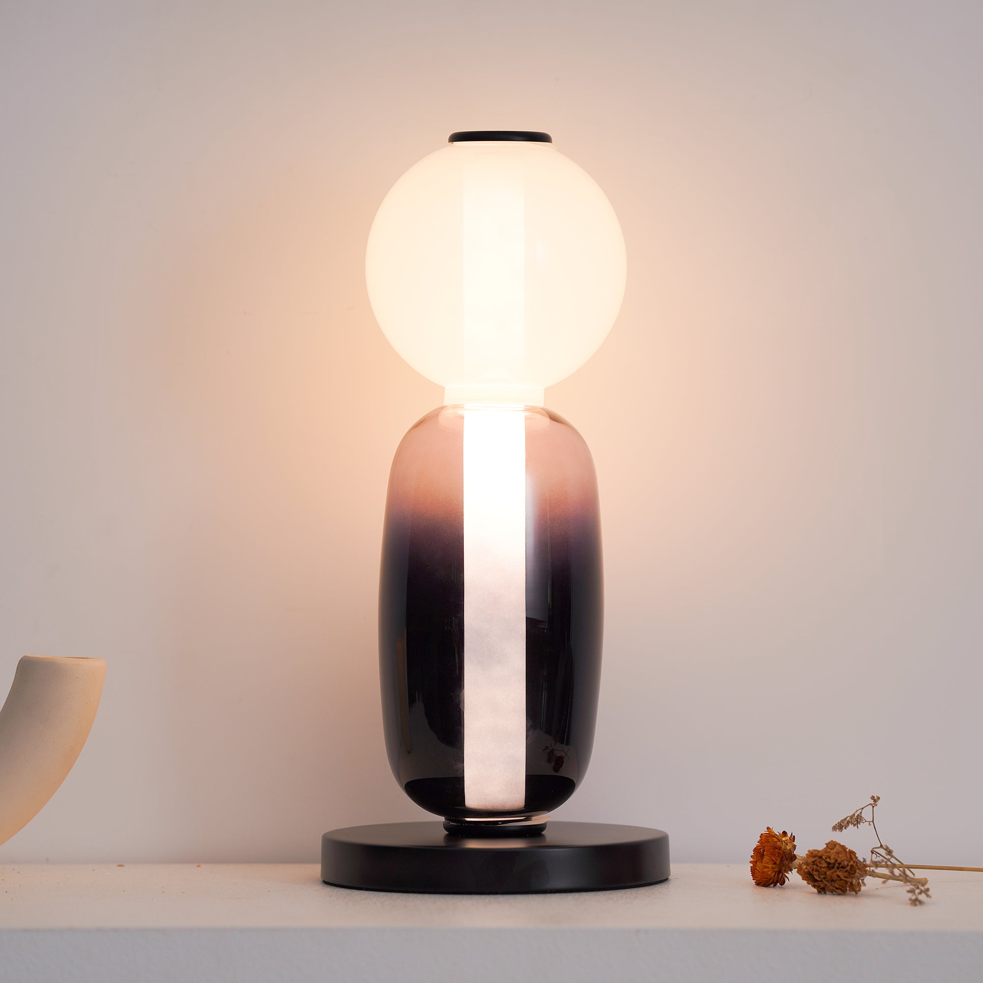 Crystal pebble table lamp lit beside a stack of books