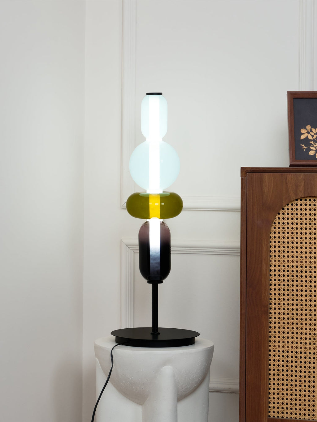 Glass cluster table lamp glowing warmly against a dark wall