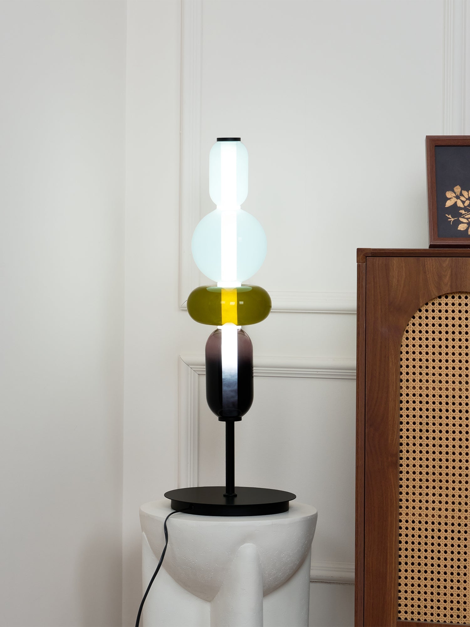 Glass cluster table lamp glowing warmly against a dark wall