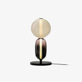 Hand-blown crystal pebble table lamp glowing on a console