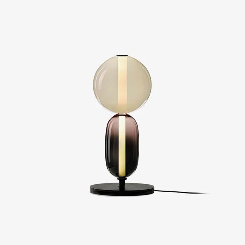 Hand-blown crystal pebble table lamp glowing on a console