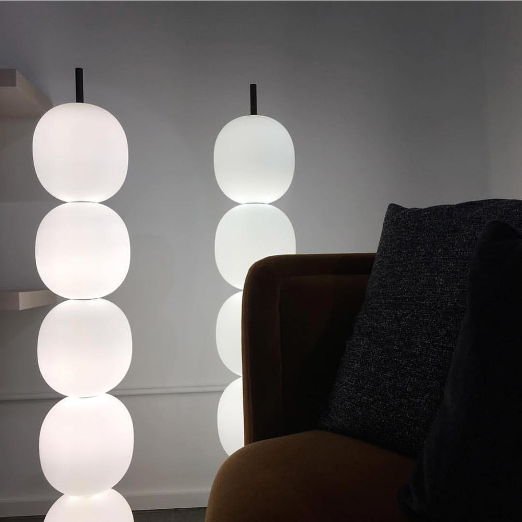 Two lit lamps close up beside an ochre velvet chair, their marble bases out of the frame.