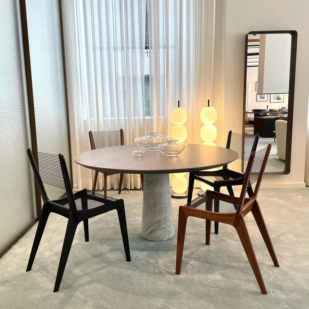 Two lit lamps behind a round dining table, the tabletop cutting across their middle globes.