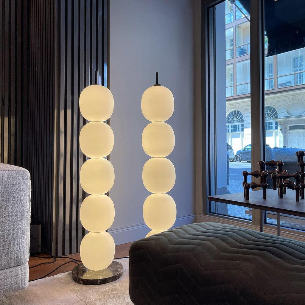 Two of the lamps lit side by side at a full-height window, the cord trailing across the floor.