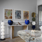 Unlit lamp beside a travertine console, its pale cord running back across the panelled wall.