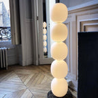 Close view of the lit lamp on star-patterned parquet, all five globes glowing by a balcony door.