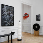 Unlit lamp in a panelled hall between a black bench and an open doorway, on parquet.