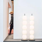 Two unlit lamps side by side on a grey display ledge, a visitor passing in blur behind them.