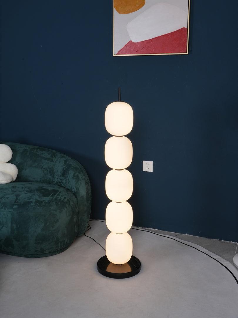 Tight view of the lit lamp against the navy wall, only the edge of the green sofa in frame.