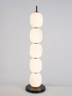 The unlit lamp on a white surface against pale grey, black stem upright above the top globe.