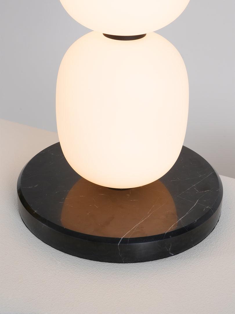 Close view of the black marble base, white veining running through it under the lowest globe.