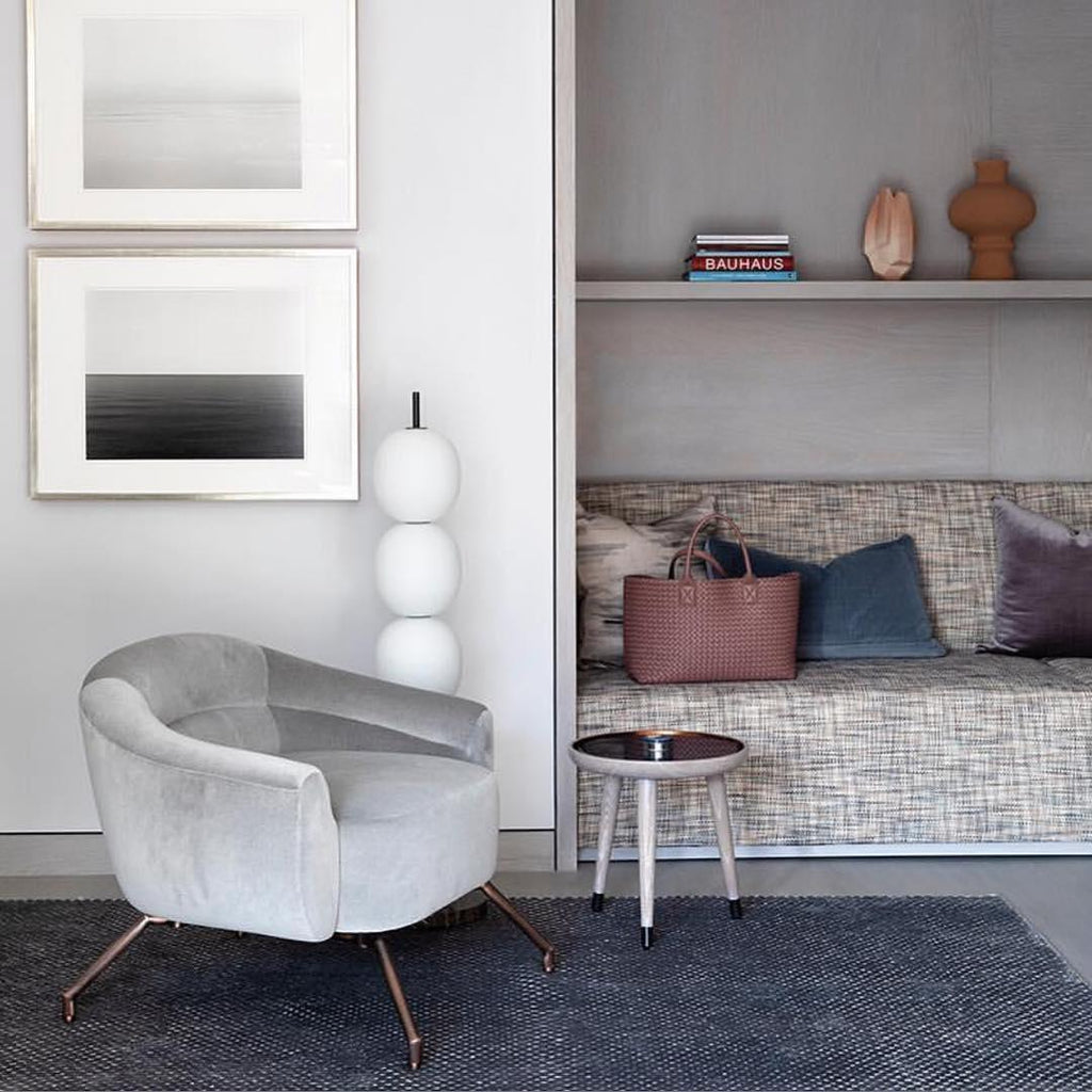 Three of the lamp's globes showing above a grey velvet armchair, beside two framed prints.