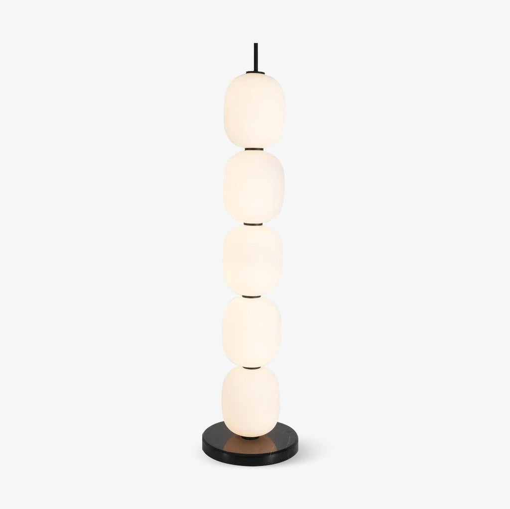 Studio view of the unlit floor lamp, five opal glass globes stacked on a black marble disc base.