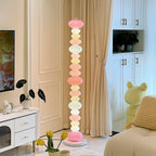 In a room with a potted plant and a yellow plush toy, this Clérachic floor lamp's pastel globes glow near a dresser.